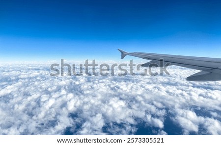 Plane flying over clouds, view from airplane window, fluffy cloudscape and blue sky background