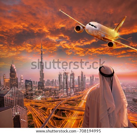 Plane is flying over Dubai against colorful sunset in United Arab Emirates