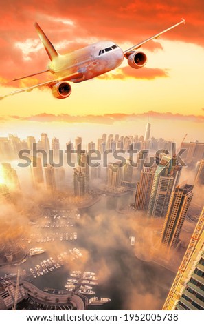 Plane is flying over Dubai Marina against colorful sunset in Dubai city, United Arab Emirates
