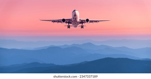 Plane is flying in pink sky at sunset. Landscape with passenger airplane over mountains ranges in fog, red sky at twilight. Aircraft is landing. Business. Aerial view. Transport. Private Jet - Powered by Shutterstock