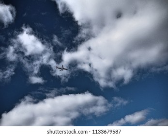 a plane flying through a cloudy blue sky