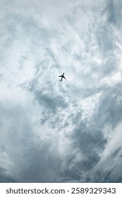 A plane is flying through a cloudy sky. The sky is mostly cloudy with some patches of blue. The plane is flying low to the ground, and it is the only object in the sky