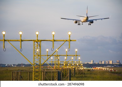 Plane Is Landing Behind The Runway Lights.