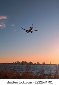 Plane Landing Towards City In A Sunset