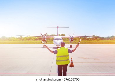 Plane On Tarmac In The Airport, Guided By Ground Staff. Taxiing