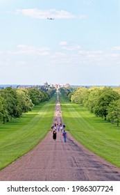 Plane over Windsor Castle viewed down the Long Walk with people enjoying the view and warm summer sun Windsor Berkshire United Kingdom - 31th of May 2021 - Travel destination UK