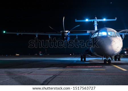 The plane stands at the airport at night by the light of lanterns