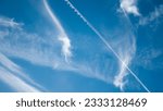 Plane trails and windy clouds in blue sky