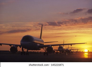 Planes Sitting On Tarmac At Sunset