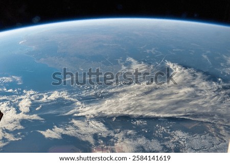 The planet appears to be covered in clouds. The blue planet is surrounded by a dark sky. Blue planet in space. The earth from space and the rising sun. Elements of this image furnished by NASA