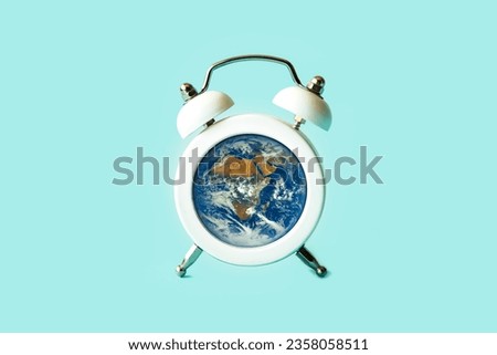 Planet Earth inside an alarm clock. Earth Hour. The concept of ecology and conservation of the planet. Image elements provided by NASA.