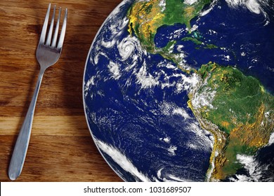 The planet Earth plate with a fork and knife on a wooden background. World hunger concept. Feed the world.