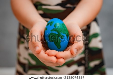 planet Earth in the shape of an egg in children's hands close-up. The concept of global problems of humanity, peace to the world, no war, military, soldier guard