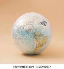 Planet Earth In Stretch Wrap Plastic With Best Before Sticker. Minimal Enviromental Concept.