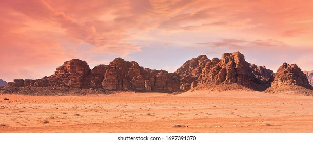 Planet Mars like landscape - Photo of Wadi Rum desert in Jordan with red pink sky above, this location was used as set for many science fiction movies - Shutterstock ID 1697391370