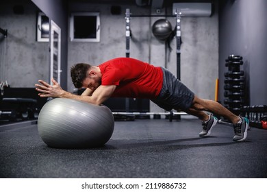 Plank position on pilates and yoga ball. A strong man in sportswear in a board position doing full body exercises and balance in a modern gym concept. Healthy lifestyle, stay in good shape, sport life