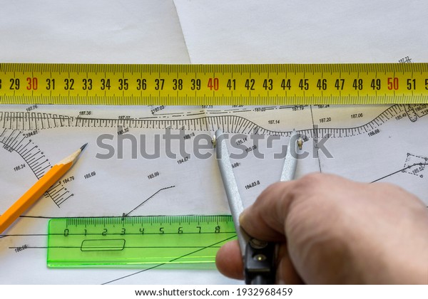 The planner checks the
dimensions on the elevation drawing with a compass. The porous
texture of the drawing paper. Yellow pencil, ruler lie on the
drawing .