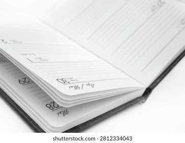 A planner is open and displayed on a flat surface. The pages show spaces for writing tasks and events. The date is written on one of the pages.