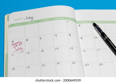 Planner schedule calendar and to do list reminder agenda work from home concept with happy July 4th handwritten down in book isolated on blue background
