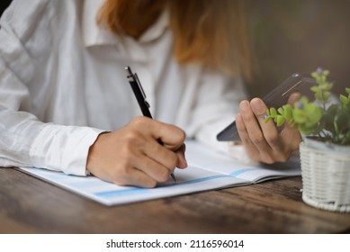 Planner using phone and write appointment to plan daily agenda calendar book. Woman Hand mark and note schedule on diary at business office desk. Coffee place on table. Work online at home concept.