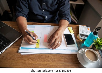 Planner writing daily appointment On 2021 Calendar book, working space at home. Hand of Asian man plan and noted schedule (holiday trip) on the diary at office desk. Calendar for planner concept.