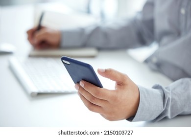Planning is always a priority if you want to succeed. Closeup shot of an unrecognisable businessman using a cellphone while writing notes in an office. - Shutterstock ID 2150103727