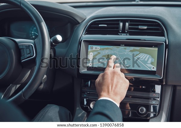 Planning the best route. Close up of man using global\
positioning system device to check the map while driving a car     \
  