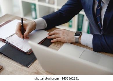 Planning the day. Close up photo of a businessman in his office writing on the page of his day planner - Powered by Shutterstock