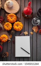 Planning to do list. Autumn mood composition on a wooden table with pumpkins, rowan and leaves. Open notepad with pen on grey wooden background