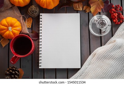 Planning to do list. Autumn mood composition on a wooden table with pumpkins, rowan and leaves. Open notepad with pen and black coffee in the red cup and on grey wooden background, warming drink