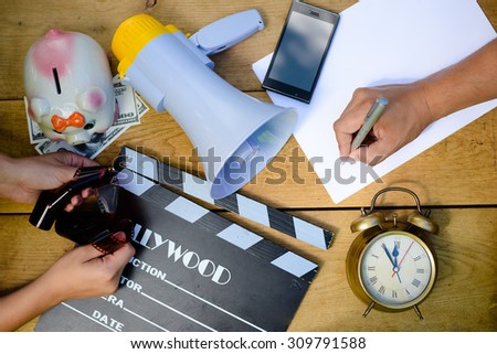 Planning to make movie with clapperboard, megaphone and piggy bank, mobile phone and alarm clock. Organize and coordinate teamwork to write scenario.
