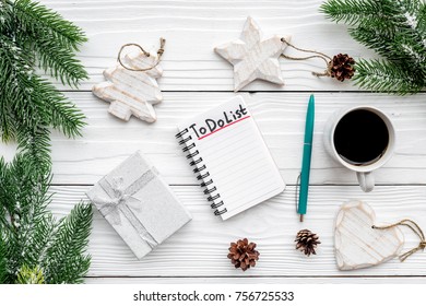 Planning new year. Notebook with to do list near christmas toys, spruce branch and pinecones on white wooden background top view