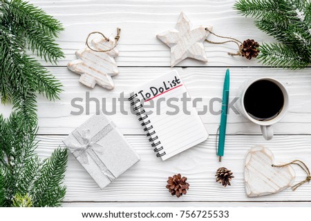 Planning new year. Notebook with to do list near christmas toys, spruce branch and pinecones on white wooden background top view