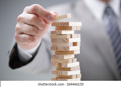 Planning, risk and strategy in business, businessman gambling placing wooden block on a tower