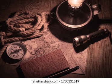 planning a trip at night at a table in the light of a kerosene lamp. Researching an old map with a compass and writing to notebook