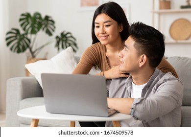 Planning Vacation. Cute Asian Couple Searching Hotel And Resort Online, Using Laptop At Home, Free Space