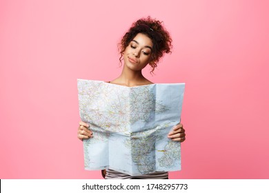 Planning Vacation. Pensive African Traveler Girl Holding Tourist Map Choosing Travel Destination Over Pink Background In Studio