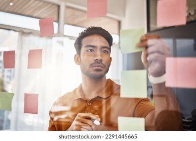 Planning, writing and focused man on glass for project management, workflow and business schedule. Asian person brainstorming ideas, moodboard and sticky notes for solution, reminder or job priority - Powered by Shutterstock