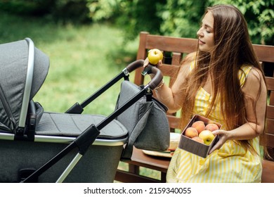 Plans And Diet For Breastfeeding Moms. Allergy In An Infant Child During Breastfeeding The Baby. Young Mom Eating Fruits While Walk With Newborn Baby In Stroller.