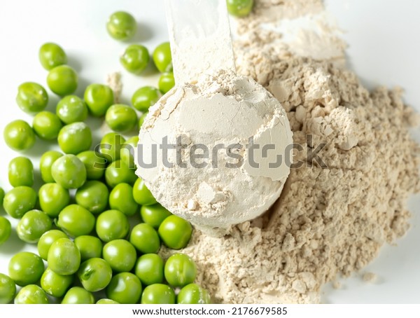 Plant base protein Pea Protein Powder in plastic scoop\
with fresh green Peas seeds on white Background, isolated copy\
space. 