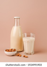 Plant based almond milk in bottle and glass on pink background. Portrait orientation