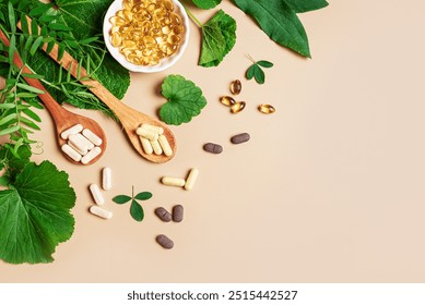 Plant based supplements. Organic vitamins. Homeopathy and alternative herbal medicine. Vegan capsules and pills, green plant leaves on beige background, top view, copy space.