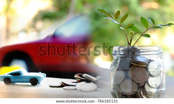 plant growing out of coins in jar with blurred\
car background.Saving money, Investment And Interest .Car loans or\
finance concept.