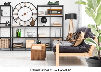 Plant next to wooden settee and table against shelves with radio and round clock on the wall in living room interior - Powered by Shutterstock