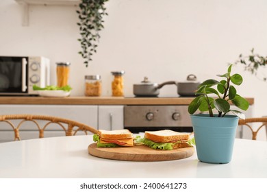 Plant with sandwiches on dining table in kitchen, closeup - Powered by Shutterstock