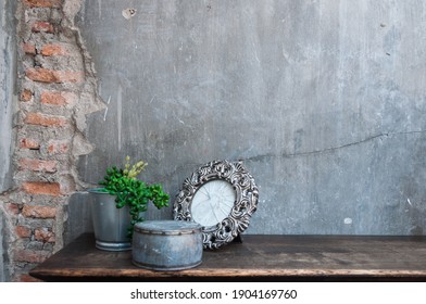 Plant In A Vase On The Wooden Table With Broken Picture Frame , Gray Concrete Wall