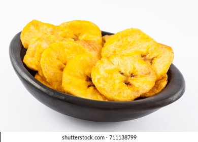 Plantain fried coins in a traditional black clay bowl isolated on white background