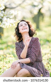 Plants, Happiness, Emotions Concept. In The Fresh Grass There Is An Dorable Woman Who Is Shrieking With Laughter, Her Radiant Smile Is Shining In The Bright Light Of Summer Sun