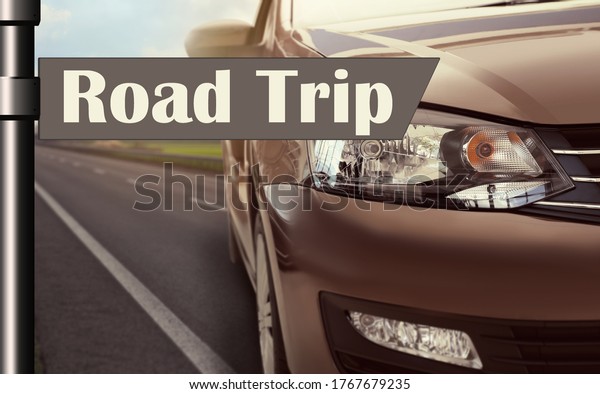 Plaque with inscription road trip. Car driving on\
asphalt highway, closeup  \
