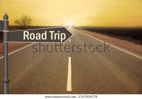 Plaque with inscription road trip on asphalt highway at\
sunset 